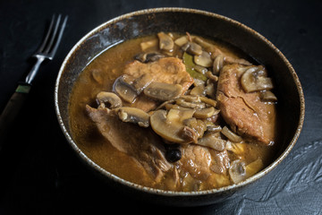 Stewed pork chop in a bright mushroom sauce.