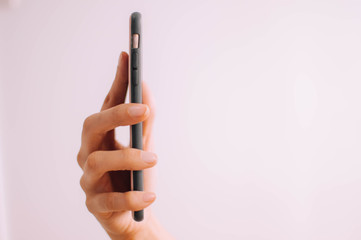 A close-up view of a young person's hand using a mobile phone on a white background