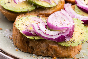 Sandwich with fresh avocado and onion on a plate