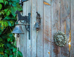 old wooden plank doors with two bells tied with a blind bell, horse outlines above the bells