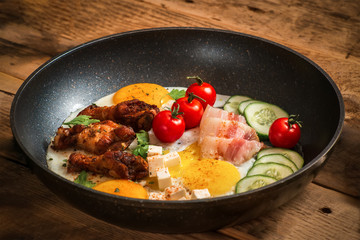 Rustic fried eggs with meat bacon and vegetables