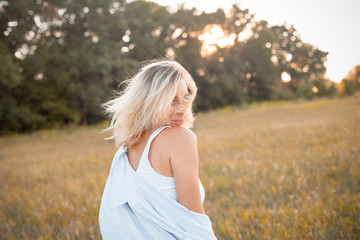 Fototapeta na wymiar Young woman in shirt walking outdoors under sunset light. Turn