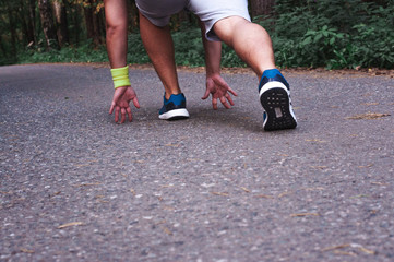 Feet step runner on the road, closeup shoes. Start running on the sidelines. Run outdoor exercise activity concept. Young handsome man jogging along a scenic path in a park.