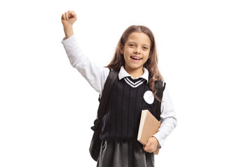 Happy little schoolgirl with a backpack and a book gesturing with hand