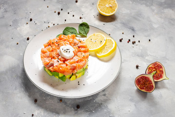 Delicious avocado and salmon tartar on concrete background