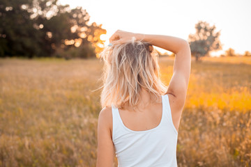 Obraz premium Young woman in white shirt looking on the sunset. Back