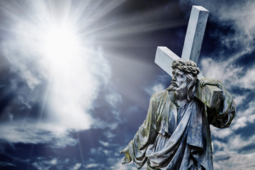 Dramatic image of the crucifixion of Jesus Christ in the rays of light. Ancient statue.