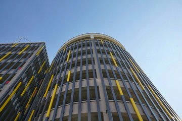 facade of multi-level colored parking with vertical decorative panels against the blue clear sky, the frame from the bottom up