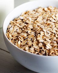 Rolled oats or oat flakes in wooden bowl