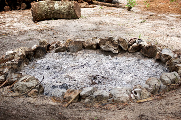 Fototapeta premium A stone circle fire pit filled with ash from recent fire.