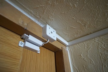 magnetically pinned white color close-up detector mounted on a wooden brown door