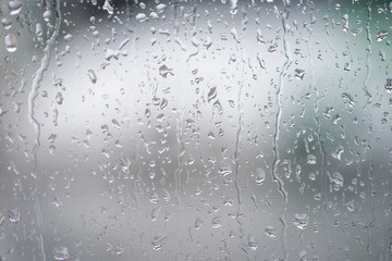 Rain drops on the window with green over background