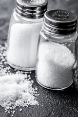 salt in glass bottle scattered on dark table background