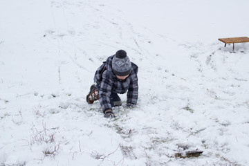 boy climbs in the snow,boy crawls on his knees through the snow to the mountain