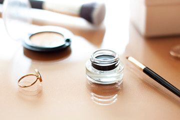 Black Gel eyeliner close up with a make up brush on the beige background - obrazy, fototapety, plakaty