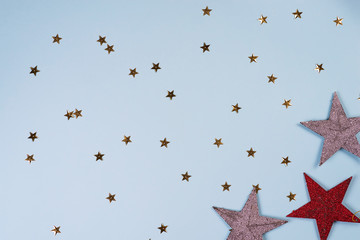 Christmas pattern made of golden, silver and red stars on blue background. Winter concept. Flat lay.