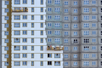 Facade work and insulation of a multistory building. Professional construction workers on the scaffold elevator insulated wall facade with mineral wool. roofers wearing safety harness insulating wall