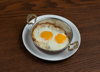 Top view of fried egg in copper pan isolated on wooden table