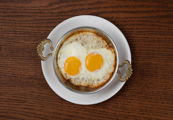 Top view of fried egg in copper pan isolated on wooden table