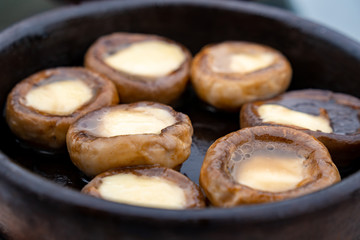 Close up mushrooms baked with cheese suluguni on ketsi. Georgian cousine.