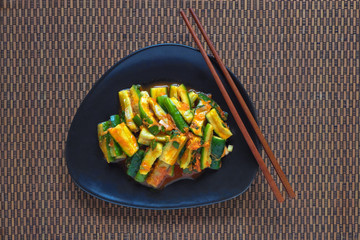 Traditional Korean cucumber kimchi snack on black plate. Top view. 