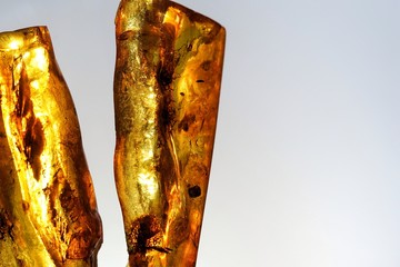 ancient amber, jeweler's stone, frozen resin, close-up background with inscription, isolated on blue background in sunshine bright yellow color with black spots