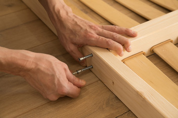 furniture, home and moving concept - close up of male hands assemblying home furniture