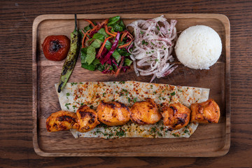 Turkish chicken sis kebab with rice and vegetables isolated on wooden table