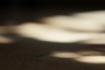 Blurred sun glare on the floor of brown laminate, in a dark room, as a background, a place for an inscription