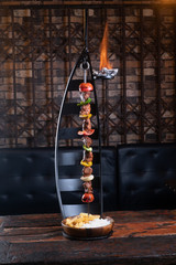 Hanging skewer kebab with rice and french fries isolated on rustic wooden table