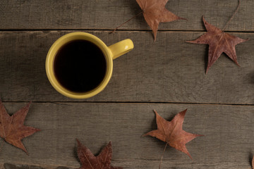 coffee on a wooden table with decorated autumn leaves
