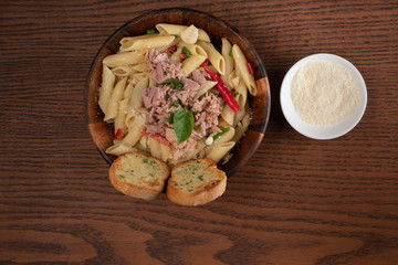 Pasta with tuna, garlic bread and parmesan cheese aside isolated on wooden background