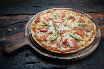 Fresh tasty pizza with chicken, tomato, paprika and mozzarella cheese isolated on rustic wooden background