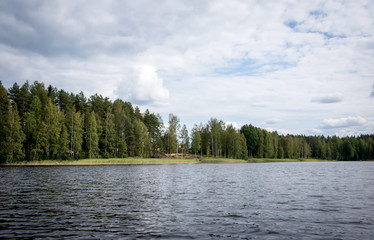 Fototapeta premium Summer view of the lake Hallanlahti with reflection of clouds on the surface of the water . Finland .