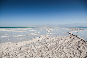 Fototapeta na wymiar Dead sea landscape with blue sky and seafront full of salt 