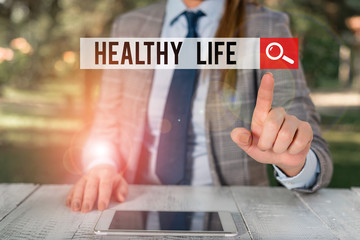 Word writing text Healthy Life. Business photo showcasing one that helps to keep and improve showing s is health or condition Female business person sitting by table holding mobile phone