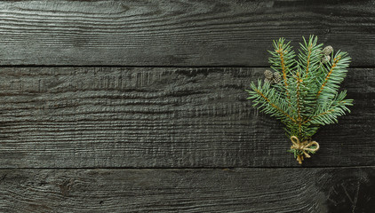 Christmas fir tree branches and pine cones on wooden dark, black background.