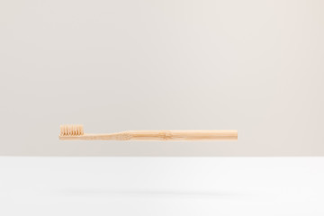 wooden toothbrush above white surface isolated on gray