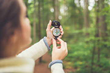Close up of female hands holding compass against forest footpath. Nature orientation concept. © zphoto83