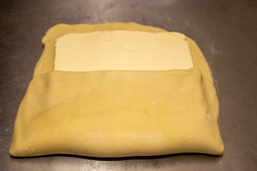 Chef hand making and folded raw puff pastry. Making puff pastry.   on a stainless steal table. First step, dough and the butter on the table.