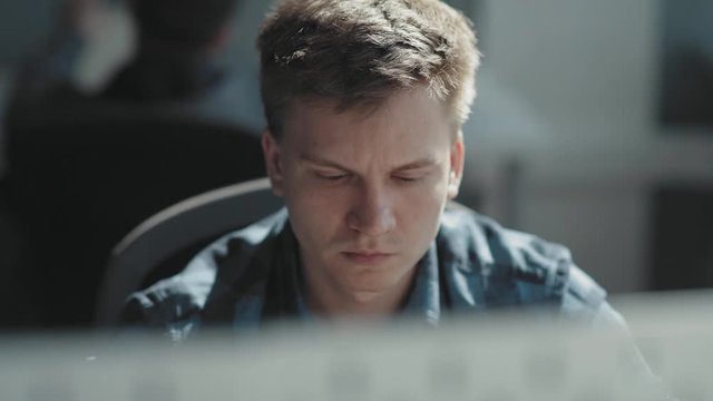 Smart man is sitting in front of a computer and is looking intently at a monitor. Manager man working at a laptop. Concept work at the computer, IT technologies, modern professions.