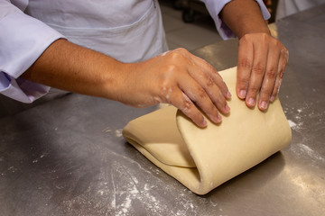 Chef hands making and folded raw puff pastry. Making puff pastry.   on a stainless steal table. First step, dough and the butter on the table.Close up. pastry chef. how to make.