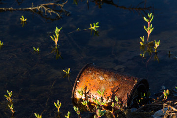 A rusty can floats in a lagoon, showing water pollution