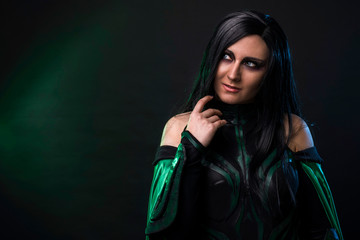 Beautiful cosplay woman in a halloween costume with green cloak.