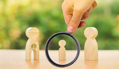 A magnifying glass looks at a child’s figure stands between father and mother. The child chooses...