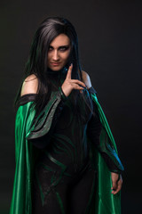 Beautiful cosplay woman in a halloween costume with green cloak.