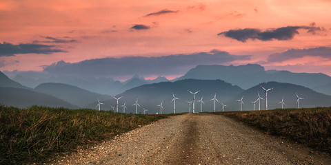 large wind farm in the atmospheric evening light in front of mist-covered mountains, in the...