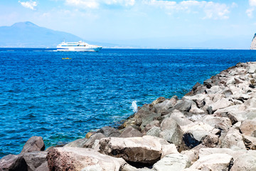 LANDSCAPE WITH ROCKS BREAKERS AND CRUISE WITH CRUISE SAILING IN THE MEDITERRANEAN SEA