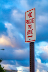 No Parking: Taxi Stand sign against clouds