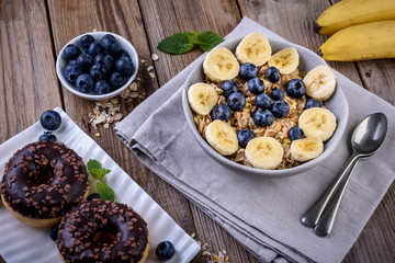 Healthy breakfast,  muesli in bowl with berry and banana on rustic wooden table